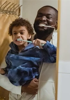 En pappa borstar tänderna tillsammans med sin son.