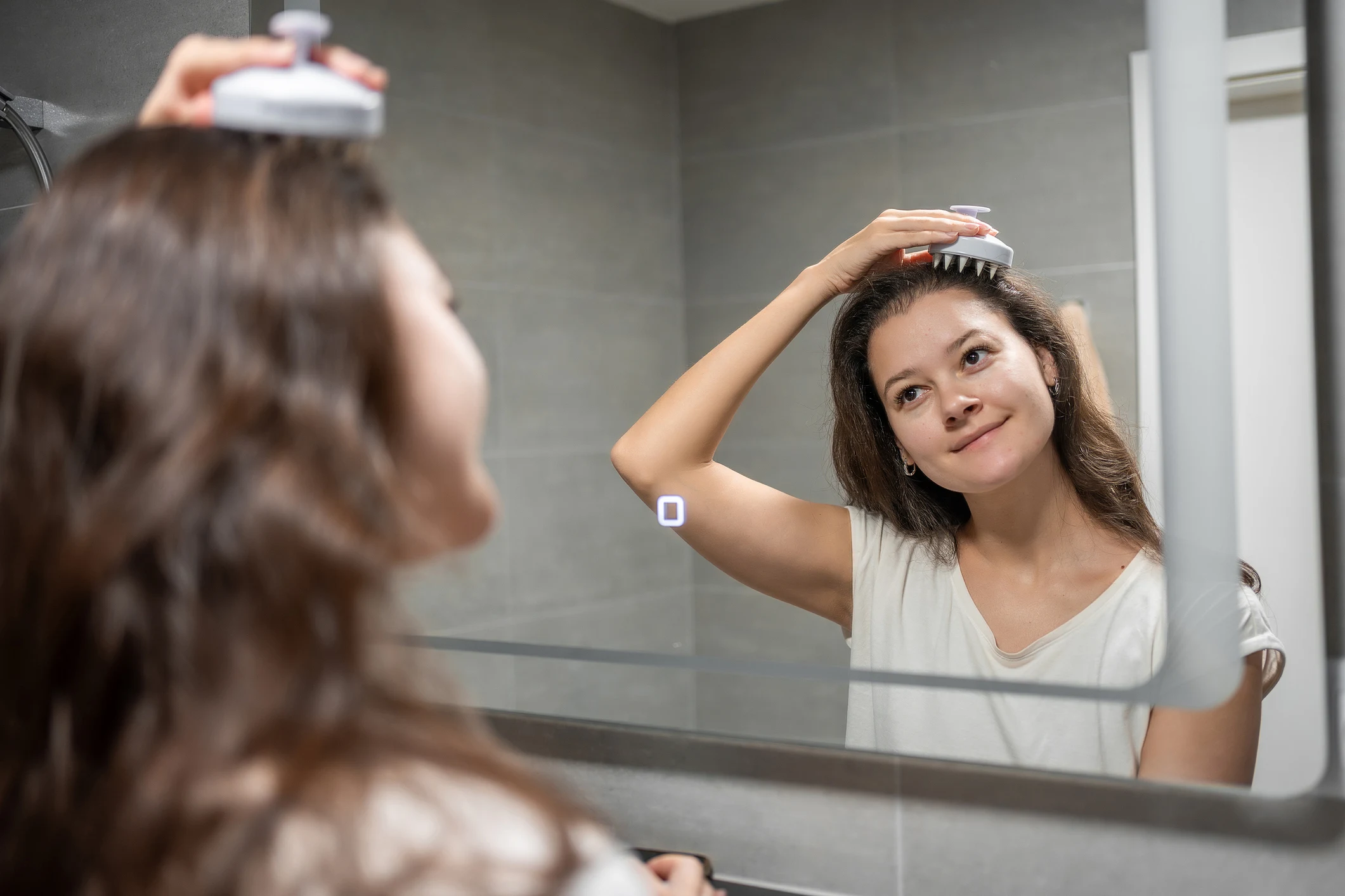 Ung kvinna som masserar hårbotten med en scalp brush.