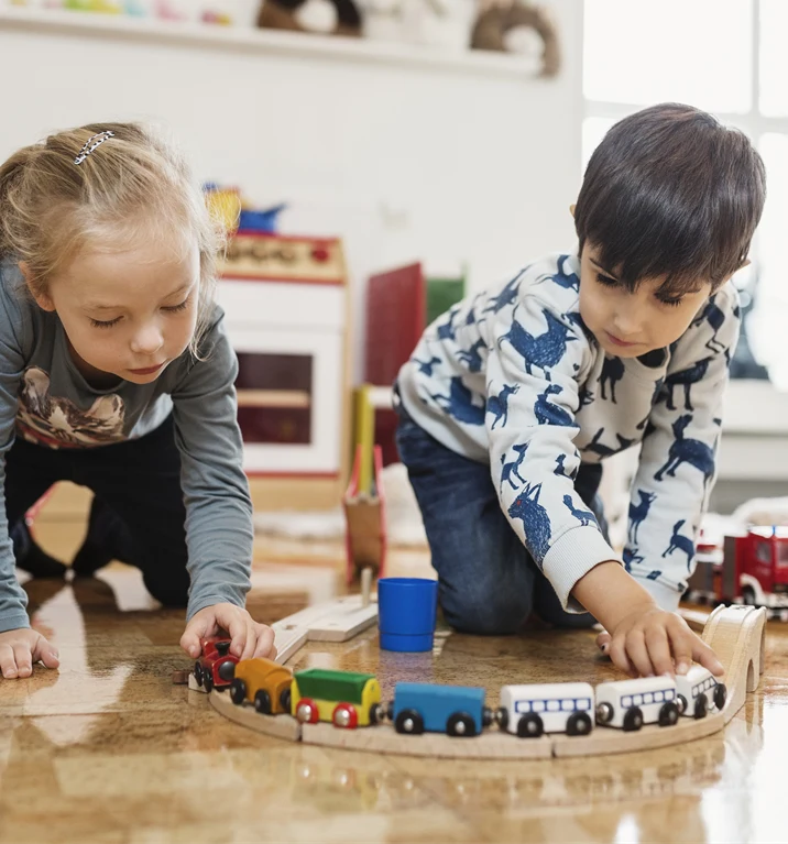 Två barn sitter på golvet i en förskola och leker med leksaker.