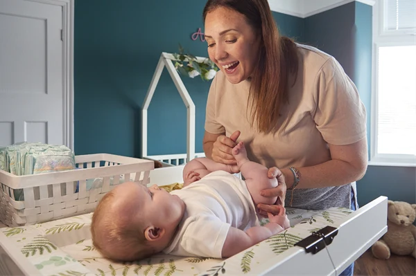 En mamma byter blöja på sitt barn. 